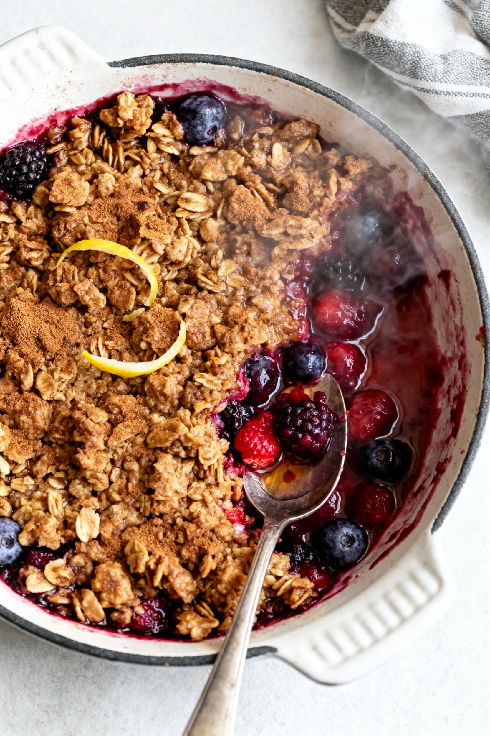 Cooking process: One-bowl mixed berry crisp just out of the oven, bubbling juices peeking through a 